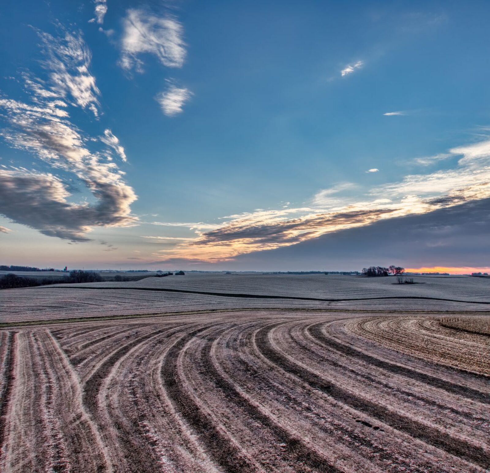 A Minnesota winter landscape with bare fields and reduced snow cover